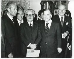["Black and white photograph print of Carl Albert standing with unidentified people."]