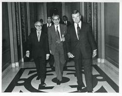 ["Black and white photograph print of Members of Egyptian Parliament walking down a hall. May 1, 1975"]