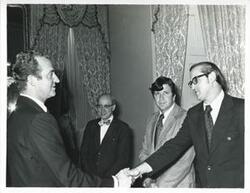["Black and white photograph print of King Juan Carlos of Spain shaking hands with an unidentified man."]