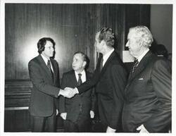 ["Black and white photograph print of King Juan Carlos of Spain shaking hands with an unidentified man as Carl Albert looks on."]