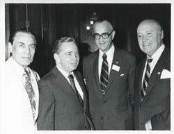 ["Black and white photograph print of Carl Albert standing with three unidentified men."]