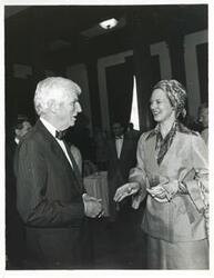 ["Black and white photograph print of Queen Margrethe of Denmark talking with an unidentified man."]