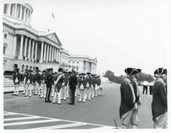 ["Black and white photograph print of several unidentified men standing in front of the Capitol."]