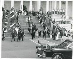["Black and white photograph print of Carl Albert, Queen Elizabeth, Nelson Rockefeller, Mike Mansfield, John Rhodes, Robert Byrd, and John Tower walking down the steps of the Capitol."]