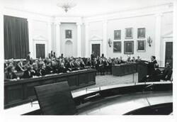 ["Black and white photograph print of Carl Albert speaking to a large group of people at an unidentified function."]
