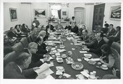 ["Black and white photograph print of several people at an unidentified function."]