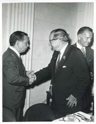 ["Black and white photograph print of Carl Albert shaking hands with an unidentified man. John Jarman is also pictured."]