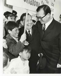 ["Black and white photograph print of Carl Albert with several unidentified children and a man during his visit to Korea."]