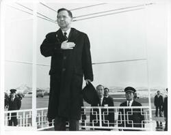["Black and white photograph print of Carl Albert standing with his hand over his heart."]