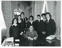 ["Black and white photograph print of Carl Albert standing with pages-Tim Collins, John Perry Sansing, Dede Dark, Jim Davis, Dennis Rainey, Debbie Uhl, and Lynn Silversmith, May 1975"]