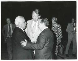 ["Black and white photograph print of Carl Albert speaking to two men during the House delegation trip. August 1975"]