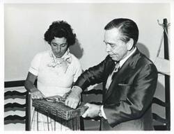 ["Black and white photograph print of Carl Albert and Jan Lipsen trying to open a present."]