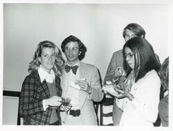 ["Black and white photograph print of Joel Jankowsky and Loise Butler standing with two other unidentified people at Carole Howard's farewell party."]