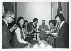 ["Black and white photograph print of Charlie Ward, Jane England Lawton, Jan Lipsen, and others eating at Lawton's farewell party. March 8, 1974"]