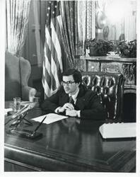 ["Black and white photograph print of Joel Jankowsky seated at a desk."]
