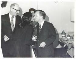 ["Black and white photograph print of Charles L. Ward, Carl Albert and Kathy Kwock at the Office Christmas party. Albert is kissing Kwock."]