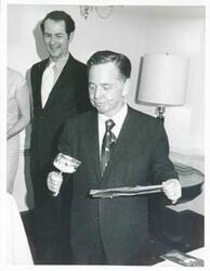 ["Black and white photograph print of Carl Albert eating candy at the office Christmas Party, 1971"]