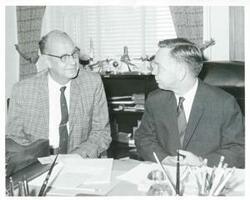 ["Black and white photograph print of Carl Albert seated at his desk and talking with Jim Robinson. September 1, 1966"]
