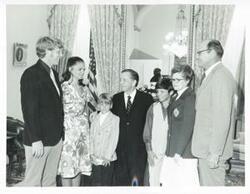 ["Black and white photograph print of Carl Albert posing with an unidentified group of people."]