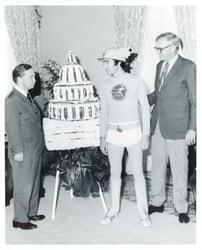 ["Black and white photograph print of Carl Albert and an unidentified man standing beside a model of the Capitol made with flowers."]