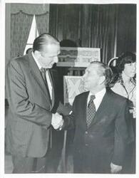 ["Black and white photograph print of Carl Albert shaking hands with an unidentified man."]