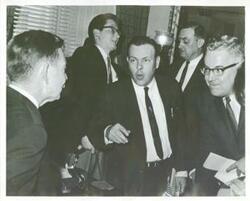 ["Black and white photograph print of Carl Albert talking with several unidentified people."]