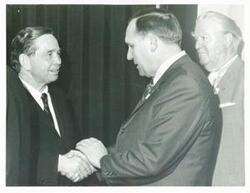 ["Black and white photograph print of Carl Albert shaking hands with an unidentified man."]