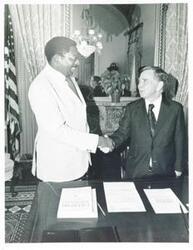 ["Black and white photograph print of Carl Albert and George Russel shaking hands in Albert's office."]
