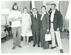 ["Black and white photograph print of Carl Albert posing with Patti Logan and her family."]