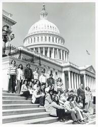 ["Black and white photograph print of Carl Albert posing with a group of people on the Capitol steps."]