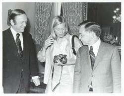 ["Black and white photograph print of Carl Albert standing with John Brademas and Susan Ford."]
