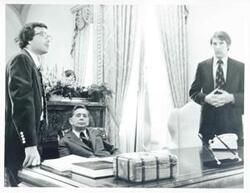 ["Black and white photograph print of Carl Albert seated at his desk. Standing beside him are Joel Jankowsky and Joe Foote."]