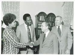 ["Black and white photograph print of Carl Albert shaking hands with Mrs. Aaron as Hank Aaron looks on. July 14, 1974"]