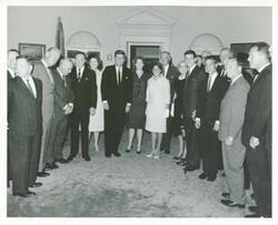 ["Black and white photograph print of Carl Albert, Les Arends, Charles Halleck, Bob Hope, Dolores Hope, and John F. Kennedy posing with a large group of people."]