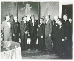 ["Black and white photograph print of President John F. Kennedy standing with a large group of men, one of which is Carl Albert."]