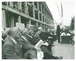 ["Black and white photograph print of Carl Albert, John F. Kennedy, Earl Warren, with others at the Rayburn building dedication. John W. McCormack is speaking."]