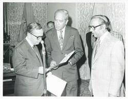 ["Black and white photograph print of Carl Albert and two unidentified men standing by a microphone, during the Bangladesh trip July 1, 1976"]