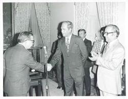 ["Black and white photograph print of Carl Albert shaking hands with an unidentified man."]