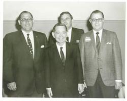 ["Black and white photograph print of Carl Albert posing with unidentified people."]