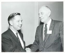 ["Black and white photograph print of Carl Albert posing with unidentified people."]