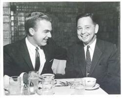 ["Black and white photograph print of Carl Albert seated at a dinner table with an unidentified man."]