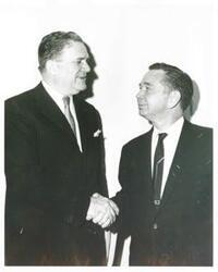 ["Black and white photograph print of Carl Albert shaking hands with an unidentified man."]
