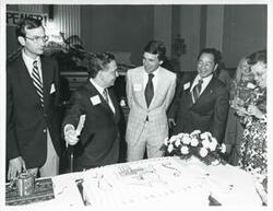 ["Black and white photograph print of Carl Albert cutting his birthday cake."]