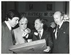 ["Black and white photograph print of Carl Albert and two unidentified men looking at one of Albert's new presents."]