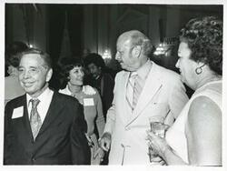 ["Black and white photograph print of Carl Albert standing with Robert L.F. Sikes and others at his birthday party, 1976"]