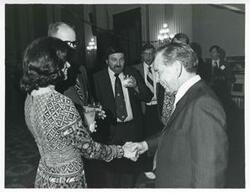 ["Black and white photograph print of Carl Albert shaking hands with an unidentified woman at his birthday party, 1976"]