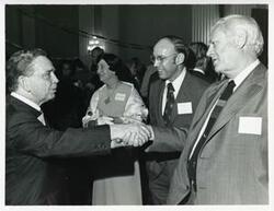 ["Black and white photograph print of Carl Albert standing with James R. Jones and others at his birthday party, 1976"]