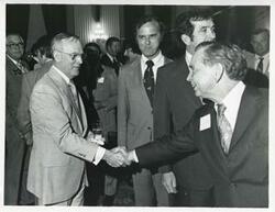 ["Black and white photograph print of Carl Albert shaking hands with an unidentified man at his birthday party, 1976"]