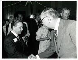 ["Black and white photograph print of Carl Albert shaking hands with an unidentified man at his birthday party, 1976"]