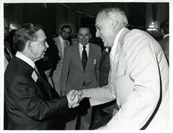 ["Black and white photograph print of Carl Albert shaking hands with an unidentified man at his birthday party, 1976"]